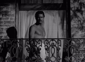 Movie still from “Viva Zapata!” (1952), directed by Elia Kazan – A man standing on a balcony looking out of a window; Medium shot, Low angle