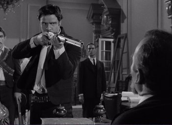 Movie still from “Viva Zapata!” (1952), directed by Elia Kazan – A man in a suit and tie holding a gun; Medium shot, Over the shoulder angle