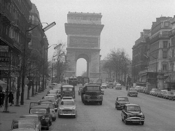 Movie still from “My Life to Live” (1962), directed by Jean-Luc Godard – A black - and - white photo of cars driving down a street; Extreme Wide shot, High angle