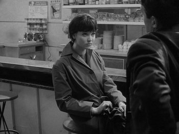 Movie still from “My Life to Live” (1962), directed by Jean-Luc Godard – A woman sitting at a counter in a restaurant; Medium shot, Over the shoulder angle