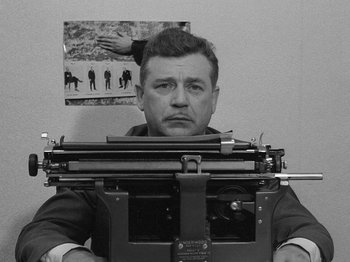 Movie still from “My Life to Live” (1962), directed by Jean-Luc Godard – A black and white photo of a man using a typewriter; Medium shot, High angle