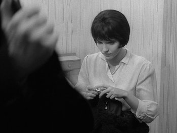 Movie still from “My Life to Live” (1962), directed by Jean-Luc Godard – A woman sitting in front of a mirror knitting; Close Up shot, Over the shoulder angle