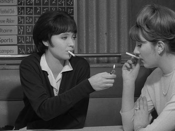 Movie still from “My Life to Live” (1962), directed by Jean-Luc Godard – Two women sitting at a table with cigarettes in their mouths; Medium shot, High angle