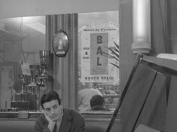 Movie still from “My Life to Live” (1962), directed by Jean-Luc Godard – A man sitting at a table in front of a mirror; Medium shot, High angle