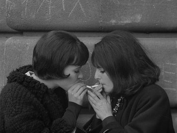 Movie still from “My Life to Live” (1962), directed by Jean-Luc Godard – Two young women are sharing a cigarette together; Medium shot, Overhead angle