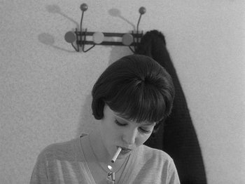Movie still from “My Life to Live” (1962), directed by Jean-Luc Godard – A woman smoking a cigarette in front of a mirror; Close Up shot, High angle