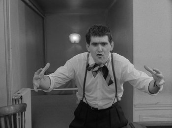 Movie still from “My Life to Live” (1962), directed by Jean-Luc Godard – A man in a tie is standing in front of an elevator; Medium shot, Low angle