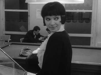 Movie still from “My Life to Live” (1962), directed by Jean-Luc Godard – A black - and - white photo of a woman in a restaurant; Medium shot, Over the shoulder angle
