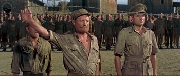 Movie still from “Von Ryan's Express” (1965), directed by Mark Robson – An old man in a hat is standing in front of a group of soldiers; Medium shot, Low angle