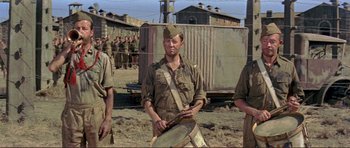 Movie still from “Von Ryan's Express” (1965), directed by Mark Robson – A man in a military uniform is playing a drum; Medium shot, Low angle