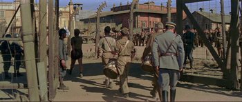 Movie still from “Von Ryan's Express” (1965), directed by Mark Robson – A group of men marching down a street; Wide shot, Over the shoulder angle