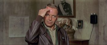 Movie still from “Von Ryan's Express” (1965), directed by Mark Robson – A man in a leather jacket saluting in front of a painting; Close Up shot, Over the shoulder angle