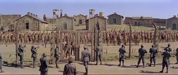 Movie still from “Von Ryan's Express” (1965), directed by Mark Robson – A group of men standing next to each other in a field; Extreme Wide shot, High angle