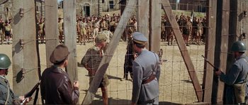 Movie still from “Von Ryan's Express” (1965), directed by Mark Robson – A group of men standing next to each other in a field; Wide shot, High angle