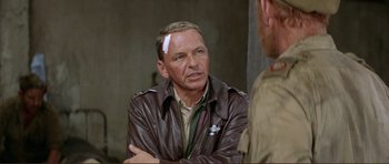 Movie still from “Von Ryan's Express” (1965), directed by Mark Robson – An older man wearing a brown leather jacket with a patch on his forehead; Close Up shot, Over the shoulder angle