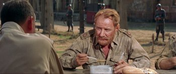 Movie still from “Von Ryan's Express” (1965), directed by Mark Robson – A man sitting at a table holding a spoon; Close Up shot, Over the shoulder angle