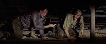 Movie still from “Von Ryan's Express” (1965), directed by Mark Robson – Two men are sitting on the ground in a dark room; Medium shot, High angle
