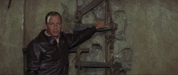 Movie still from “Von Ryan's Express” (1965), directed by Mark Robson – A man in a leather jacket pointing to a wall; Medium shot, Low angle