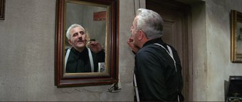 Movie still from “Von Ryan's Express” (1965), directed by Mark Robson – An older man brushing his teeth in front of a mirror; Medium shot, Low angle