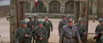 Movie still from “Von Ryan's Express” (1965), directed by Mark Robson – A group of men dressed in military uniforms walk down a street; Wide shot, High angle