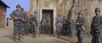 Movie still from “Von Ryan's Express” (1965), directed by Mark Robson – A group of men in uniform standing in front of a building; Wide shot, High angle