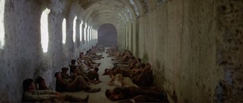 Movie still from “Von Ryan's Express” (1965), directed by Mark Robson – A group of men sitting on the floor of a building; Wide shot, High angle