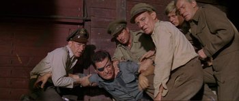 Movie still from “Von Ryan's Express” (1965), directed by Mark Robson – A group of men standing next to each other on a wall; Medium shot, High angle