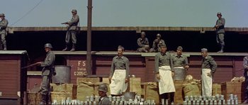 Movie still from “Von Ryan's Express” (1965), directed by Mark Robson – Men in aprons standing on a train platform; Wide shot, Low angle
