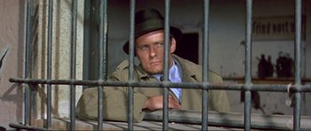 Movie still from “Von Ryan's Express” (1965), directed by Mark Robson – A man wearing a hat sitting in a jail cell; Close Up shot, High angle