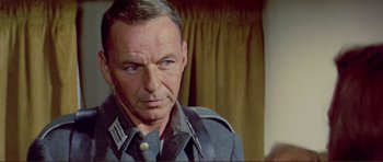 Movie still from “Von Ryan's Express” (1965), directed by Mark Robson – An older man wearing a uniform looking at the camera; Close Up shot, Over the shoulder angle