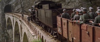Movie still from “Von Ryan's Express” (1965), directed by Mark Robson – A man in a helmet stands on the side of a train; Extreme Wide shot, High angle