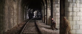 Movie still from “Von Ryan's Express” (1965), directed by Mark Robson – A man kneeling down next to train tracks; Wide shot, High angle