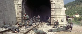 Movie still from “Von Ryan's Express” (1965), directed by Mark Robson – A group of soldiers are sitting and kneeling on train tracks; Wide shot, High angle