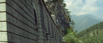 Movie still from “Von Ryan's Express” (1965), directed by Mark Robson – A man standing on a ledge of a stone wall; Extreme Wide shot, Low angle