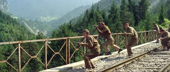 Movie still from “Von Ryan's Express” (1965), directed by Mark Robson – A couple of men are standing on a train track; Wide shot, Low angle