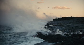 Movie still from “Voyage of Time” (2016), directed by Terrence Malick – Waves crashing on the shore of the ocean at sunset; Extreme Wide shot, High angle
