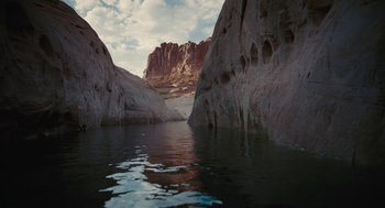 Movie still from “Voyage of Time” (2016), directed by Terrence Malick – A body of water surrounded by mountains and a cloudy sky; Extreme Wide shot, High angle