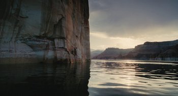 Movie still from “Voyage of Time” (2016), directed by Terrence Malick – A body of water with a rock wall in the background; Extreme Wide shot, High angle