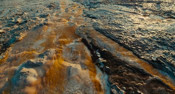 Movie still from “Voyage of Time” (2016), directed by Terrence Malick – A body of water covered in brown and yellow water; Extreme Wide shot, Overhead angle