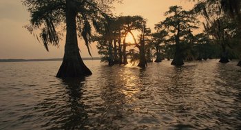 Movie still from “Voyage of Time” (2016), directed by Terrence Malick – The sun is setting over a body of water; Extreme Wide shot, Low angle