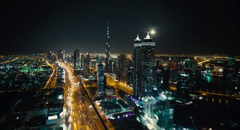 Movie still from “Voyage of Time” (2016), directed by Terrence Malick – An aerial view of a city at night with a full moon in the background; Extreme Wide shot, High angle