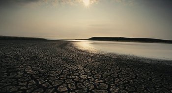 Movie still from “Voyage of Time” (2016), directed by Terrence Malick – The sun is setting over a body of water; Extreme Wide shot, High angle