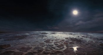 Movie still from “Voyage of Time” (2016), directed by Terrence Malick – A view of the ocean at night with the moon in the background; Extreme Wide shot, High angle