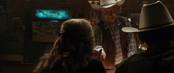 Movie still from “W.” (2008), directed by Oliver Stone – A man wearing a cowboy hat is talking to a woman in front of him; Medium shot, Over the shoulder angle
