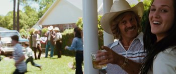 Movie still from “W.” (2008), directed by Oliver Stone – An older woman wearing a cowboy hat holding a drink; Medium shot, Over the shoulder angle