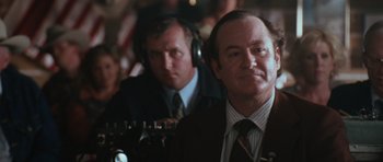 Movie still from “W.” (2008), directed by Oliver Stone – Two men in suits and ties are listening to music; Close Up shot, Over the shoulder angle