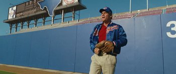 Movie still from “W.” (2008), directed by Oliver Stone – An older baseball player holding a catchers mitt; Medium shot, Low angle
