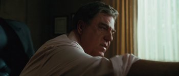 Movie still from “W.” (2008), directed by Oliver Stone – A person sitting in a room; Close Up shot, Low angle