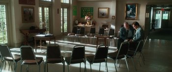 Movie still from “W.” (2008), directed by Oliver Stone – Many chairs in this room with a table in the background; Extreme Wide shot, High angle