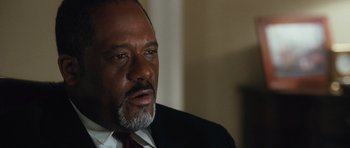 Movie still from “W.” (2008), directed by Oliver Stone – A man in a suit and tie looking at the camera; Close Up shot, Low angle